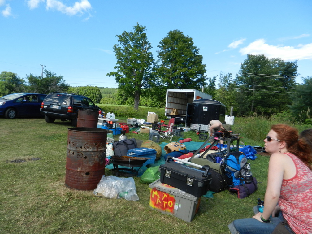 A volunteer sits by a pile of gear near Upper Parking.