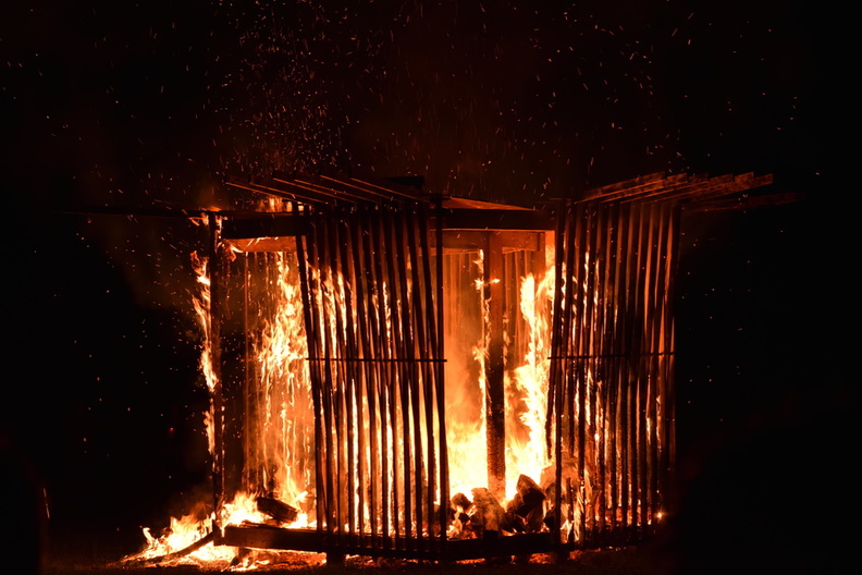 A wooden structure burns at nighttime.