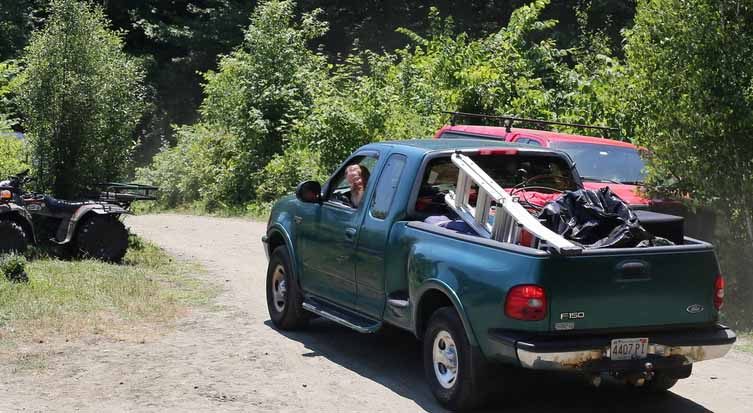 A loaded pickup truck drives along a path.