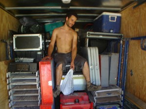 A Firefly sits on a pile of gear in the cargo area of a moving truck.