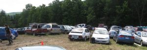 Dozens of cars parked on a field.