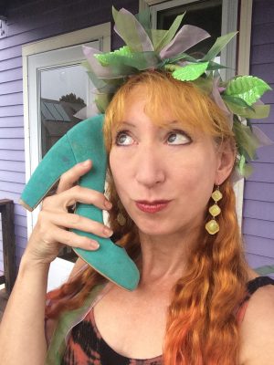 A volunteer holds a high-heeled shoe to their ear like a telephone.